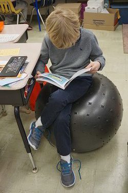 student reading on exercise ball chair